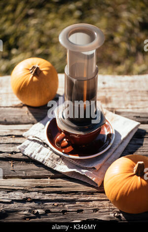 Café en plein air d'automne pique-nique. Tasses à café, jolie petite citrouille sur l'ancienne table background Banque D'Images