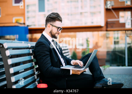Man avec son ordinateur et de boire du café sur un banc Banque D'Images
