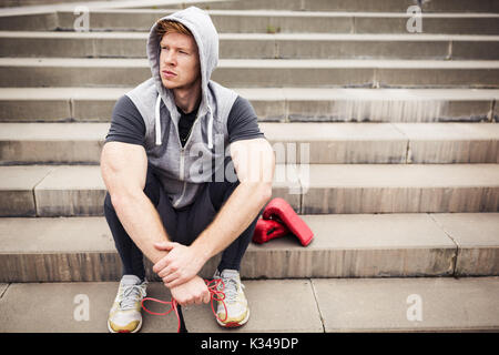 Une photo du jeune homme assis sur l'escalier et faire une pause au cours de la pratique de la boxe. Banque D'Images