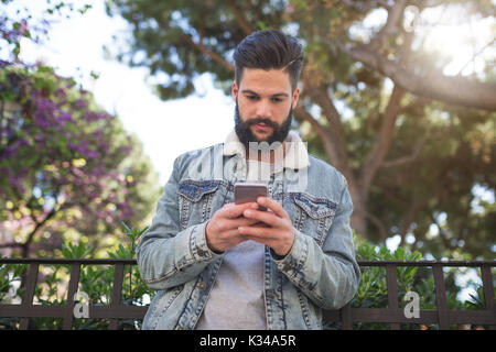Une photo de jeune, beau homme debout sur l'allée du park et de sms. Banque D'Images