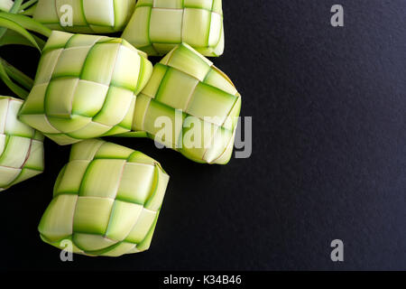 Boulette de riz de tubages ou également connu comme ketupat fabriqués à partir de feuilles de cocotiers sur fond noir. Ketupat est un type de boulette de riz, paniers-insi Banque D'Images