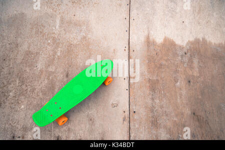 Penny vert unique sur un half-pipe en bois. Banque D'Images