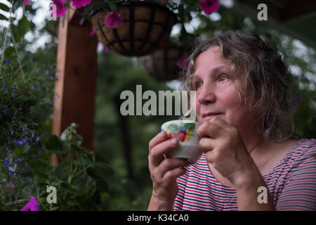 Senior woman in green garden avec des fleurs dans les mains Banque D'Images