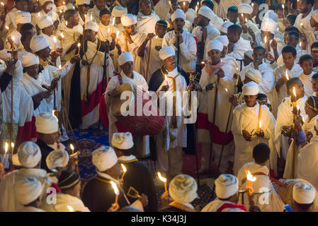 Prêtres chantant des prières aux chandelles dans la cour de l'église Medhane Alem, Pari pendant les prières sur le samedi de Pâques orthodoxe éthiopienne, Lalibela, Éthiopie Banque D'Images