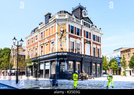 Archway Tavern et nettoyeurs de rue avec tuyaux à pression dans le navigateur 'Carré', la suppression de la gomme à partir du nouveau-centre piétonnier d'Archway, Londres Banque D'Images