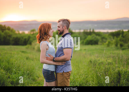 Jeune couple pour le coucher du soleil dans la prairie Banque D'Images