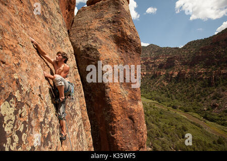 Un jeune, male rock climber conduisant un itinéraire dans un canyon Red Rock dans l'ouest de l'Unitre Membres. Banque D'Images