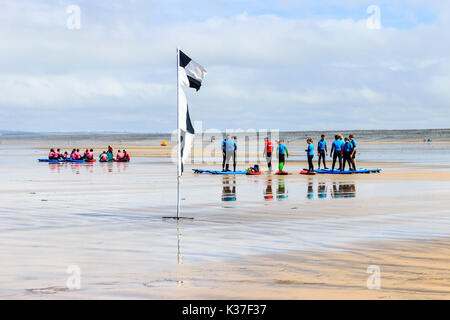 Avertissement en damier noir et blanc d'un drapeau et d'une école de surf session sur la plage à Westward Ho !, Devon, England, UK Banque D'Images