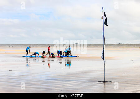 Avertissement en damier noir et blanc d'un drapeau et d'une école de surf session sur la plage à Westward Ho !, Devon, England, UK Banque D'Images