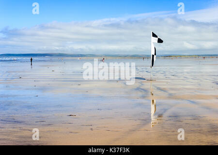 Avertissement en damier noir et blanc drapeau sur la plage de sable à marée basse, Westward Ho !, Devon, England, UK Banque D'Images