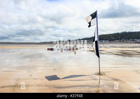 Avertissement en damier noir et blanc drapeau sur la plage de sable à marée basse, Westward Ho !, Devon, England, UK Banque D'Images