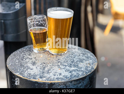 Pinte britannique et demi pinte de bière reposant sur une table, Royaume-Uni Banque D'Images