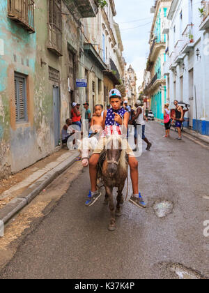 Scène de rue à La Havane, deux jeunes garçons cubains équitation sur poneys à travers une rue de Habana Vieja, Cuba Banque D'Images