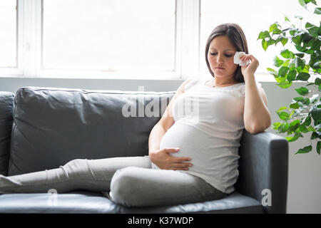 Triste pregnant woman lying on sofa at home Banque D'Images