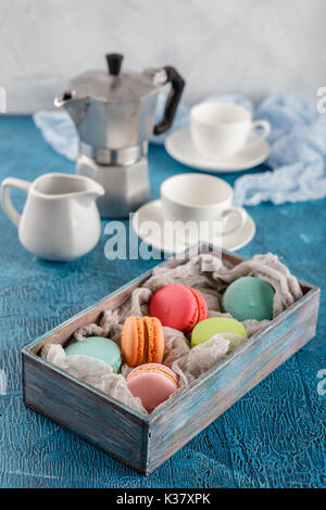 Le Français classique du maquereau colorés les cookies dans la boîte en bois, tasses pour le café et le métal cafetière sur fond bleu Banque D'Images