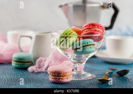 Le Français classique du maquereau colorée cookies en vase en verre, des tasses pour le café et le métal cafetière sur fond bleu Banque D'Images