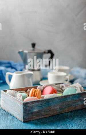Le Français classique du maquereau colorés les cookies dans la boîte en bois, tasses pour le café et le métal cafetière sur fond bleu Banque D'Images