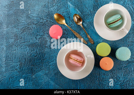Le Français classique du maquereau et tasses colorées des cookies pour le café sur fond bleu Banque D'Images