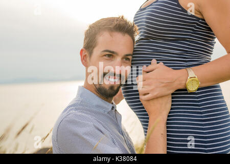 Femme enceinte à plage avec mari s'amusant Banque D'Images