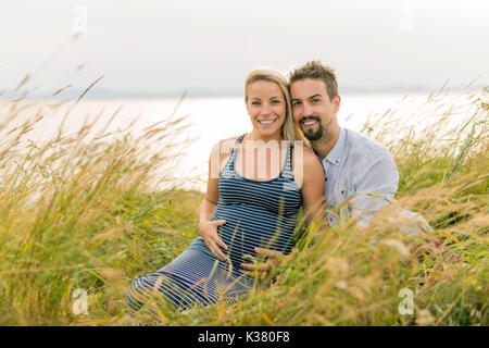 Femme enceinte à plage avec mari s'amusant Banque D'Images