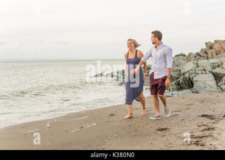 Femme enceinte à plage avec mari s'amusant Banque D'Images