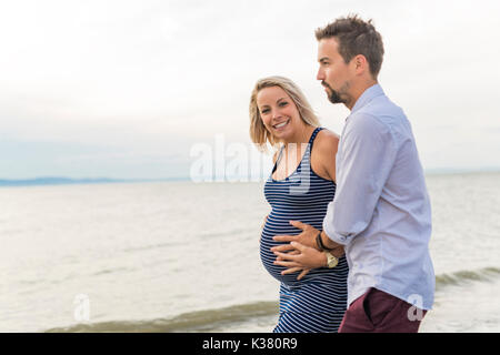 Femme enceinte à plage avec mari s'amusant Banque D'Images