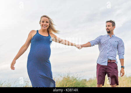 Femme enceinte à plage avec mari s'amusant Banque D'Images