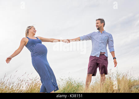 Femme enceinte à plage avec mari s'amusant Banque D'Images