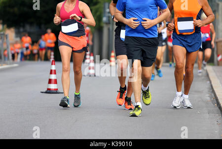 Coureurs, garçons et filles, de fonctionner avec un short et baskets le long des routes de la ville pendant le marathon Banque D'Images