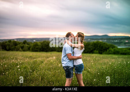 Jeune couple pour le coucher du soleil dans la prairie Banque D'Images