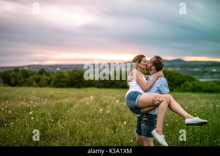 Jeune couple pour le coucher du soleil dans la prairie Banque D'Images