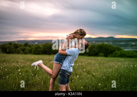 Jeune couple pour le coucher du soleil dans la prairie Banque D'Images