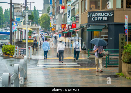 TOKYO, JAPON - 28 juin 2017 : personnes non identifiées sous des parasols sur zebra crossing street dans le quartier de Jimbocho situé à Tokyo Banque D'Images