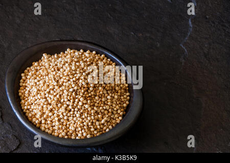 Les graines de quinoa soufflé (Chenopodium quinoa) dans un plat d'argile noire Banque D'Images