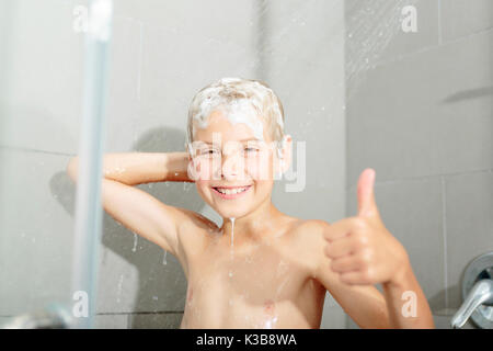 Happy teen boy lave-tête de douche dans la salle de bains Banque D'Images