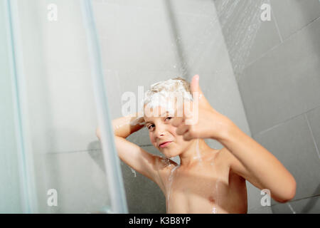 Happy teen boy lave-tête de douche dans la salle de bains Banque D'Images