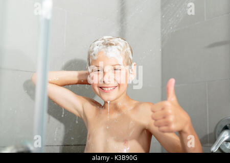 Happy teen boy lave-tête de douche dans la salle de bains Banque D'Images