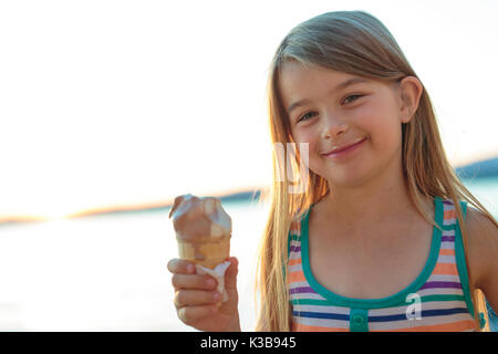 Belle petite fille mange de la glace en été Banque D'Images