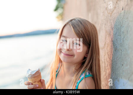 Belle petite fille mange de la glace en été Banque D'Images