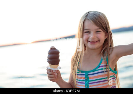 Belle petite fille mange de la glace en été Banque D'Images