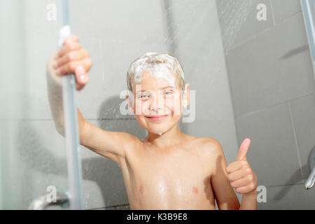 Happy teen boy lave-tête de douche dans la salle de bains Banque D'Images