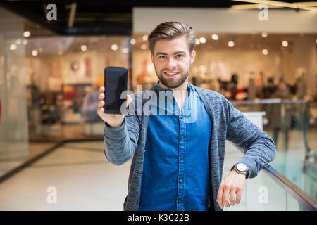 Une photo de jeune homme Présentation de smartphone. Il est souriant. Banque D'Images