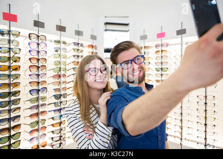 Une photo de jeune couple qui eux-mêmes d'une photo à l'opticien. Banque D'Images