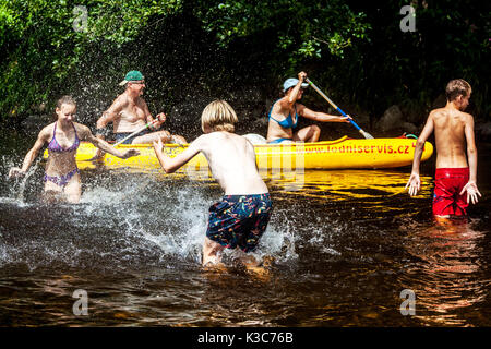 Les adolescents aux projections d'eau à l'autre dans l'Otava river, en passant sur les aînés dans un canot, République Tchèque Banque D'Images