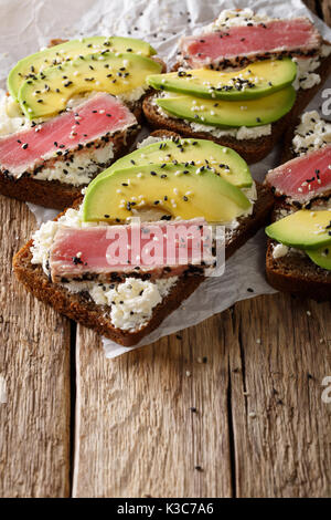 Des sandwichs au thon steak dans le sésame, l'avocat et le fromage à la crème sur une table verticale. Banque D'Images