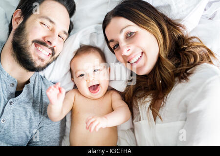 Père Mère et bébé enfant sur un lit blanc. Banque D'Images