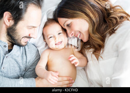 Père Mère et bébé enfant sur un lit blanc. Banque D'Images