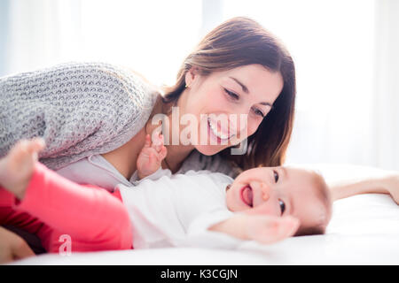 Mère et bébé enfant sur un lit blanc.