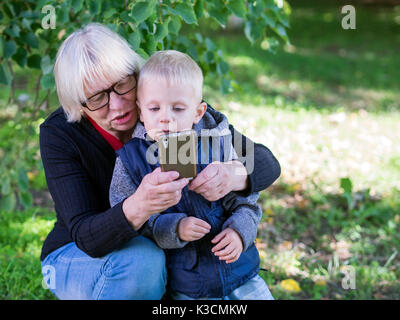 Middle-aged woman selfies montre avec son petit-fils dans le parc Banque D'Images