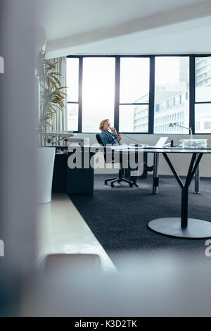 Businesswoman sitting in office et parler sur téléphone fixe. Young woman using mobile phone in office. Banque D'Images